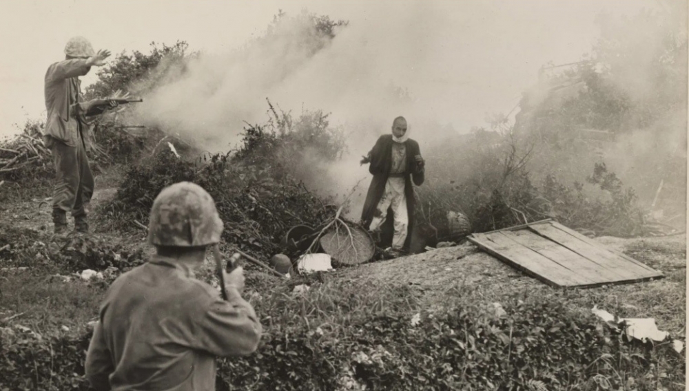 ▲ 1945년 3월경 오키나와 전투 중, 미해병이 숨어 있던 굴에서 일본군이 나오자 동료에게 사격을 중지하라는 손짓을 보내고 있다./사진제공=미국국립문서보관소