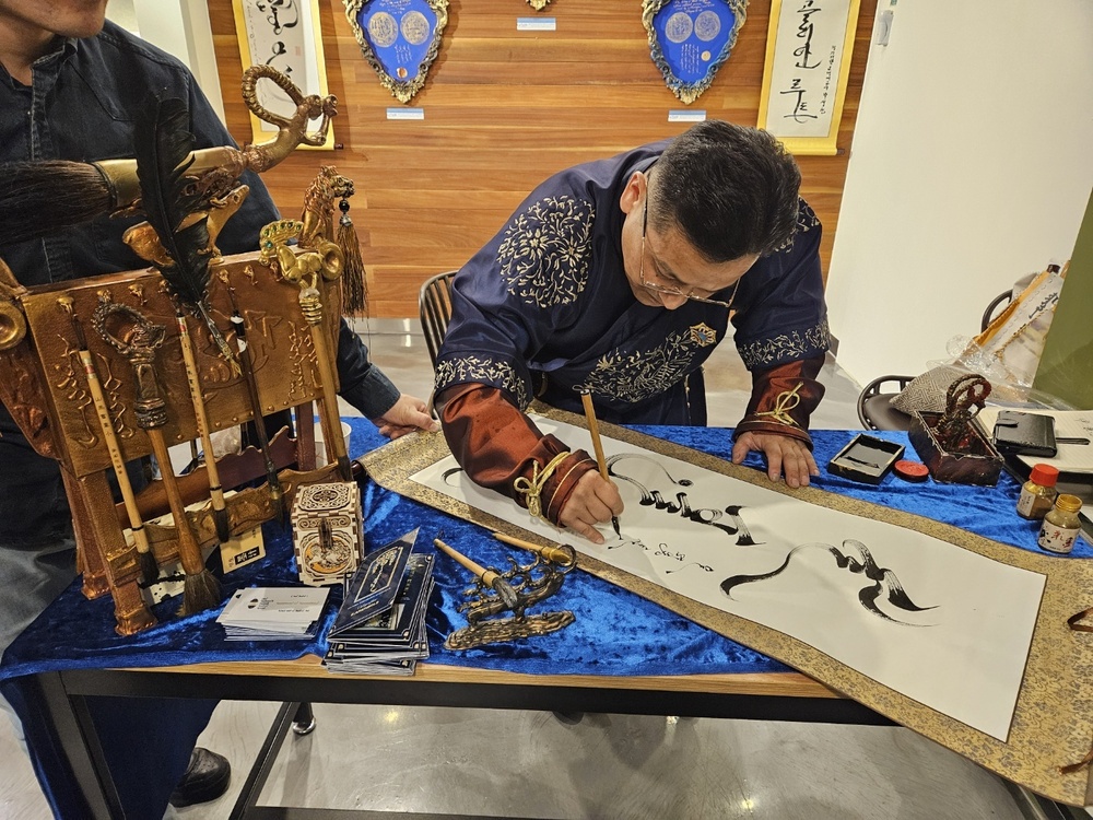 ▲ 몽골 문화사절 아리운볼트 에르드네후약이 이날 행사에 참석한 이윤규 총장의 이름을 몽골어로 직접 쓰고 있는 모습.